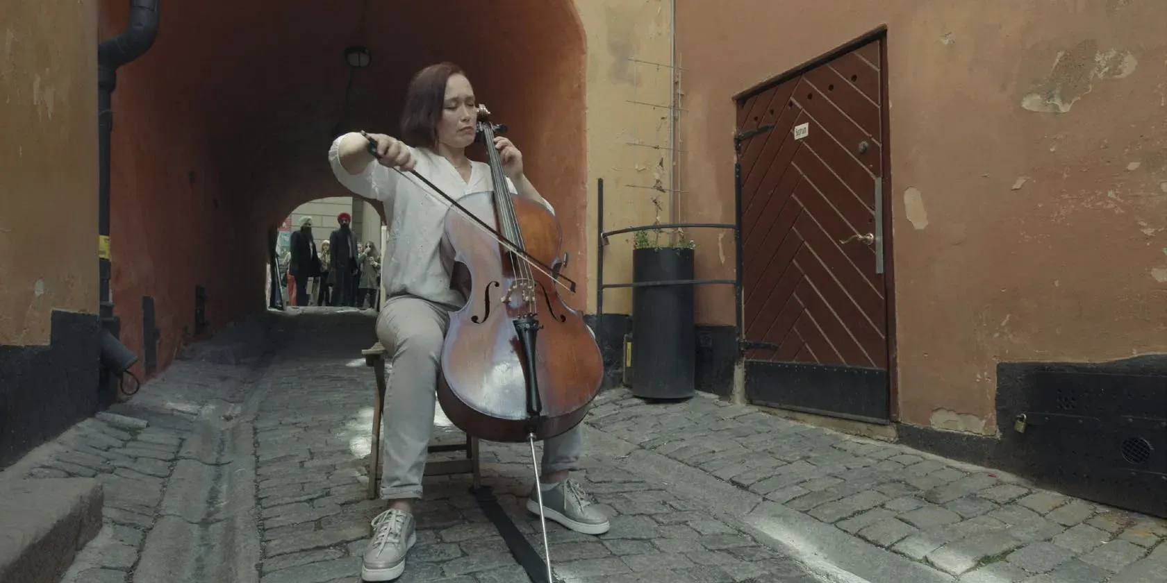 A cellist playing alone in a cobbled Stockholm alley